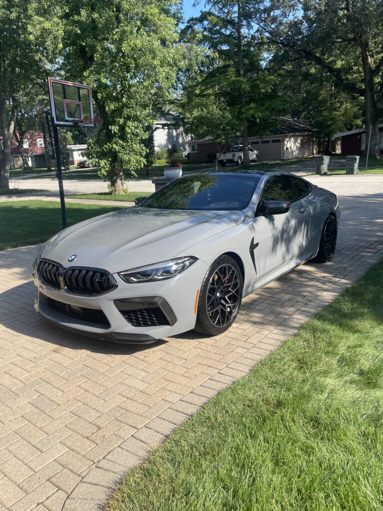 Gray BMW car parked on brick driveway